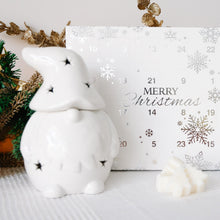Load image into Gallery viewer, Decorative Advent calendar with snowflake designs and a white Christmas Gonk shaped wax melt burner sitting in front.