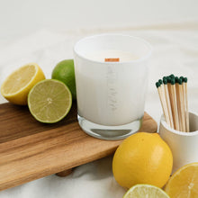 Load image into Gallery viewer, A picture of a medium candle with a wooden wick in a white glass vessel with MJM Home Fragrance logo.  The candle is surrounded by citrus fruits to depict the scent notes