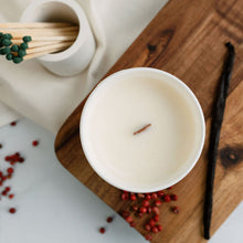 Load image into Gallery viewer, A birds eye view picture of a medium candle with a wooden wick surrounded by ingredients depicting vanilla and pink peppercorns