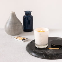 Load image into Gallery viewer, An image of a lit small candle with a wooden wick, inside a white glass vessel with MJM Home Fragrance logo
