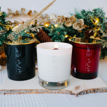 Load image into Gallery viewer, Three candles in emerald green, white, and red containers with a Christmas-themed background.
